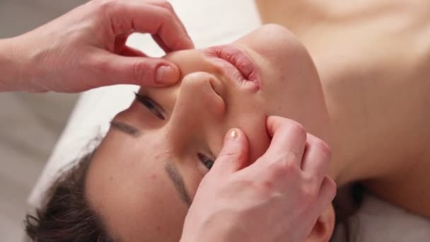 Kosmetolog vyrábí bukové masáže pacientů na obličejové svaly. — Stock video