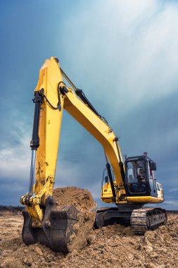 İnşaat alanında taş ocağında büyük bir sarı renkli kazıcı var. Sanayi görüntüsü