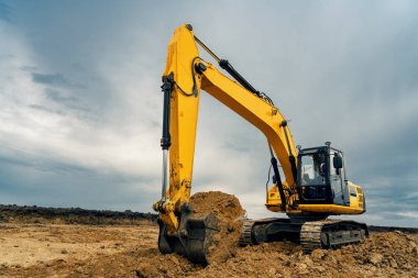 İnşaat alanında taş ocağında büyük bir sarı renkli kazıcı var. Sanayi görüntüsü