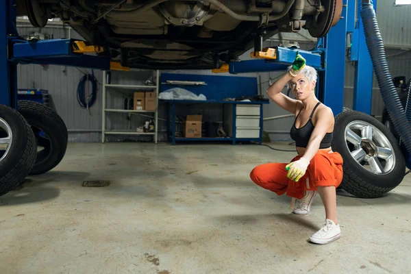 Сексуальна молода жінка ремонтує машину в автосервісі — стокове фото