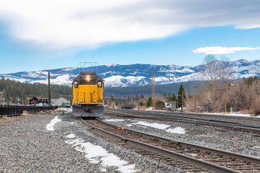A locomotive crossing in Truckee, Nevada, with snowy mountains in background clipart