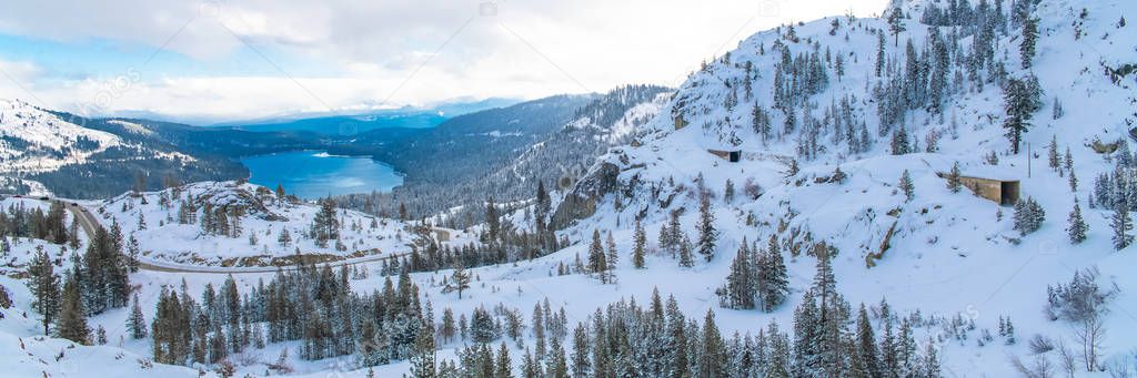 The Donner lake under the snow in winter, in California, panorama, with tunnels in the mountain for the train