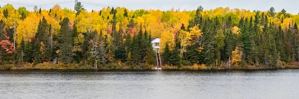 House hidden in the forest on the lake in Canada, in autumn, beautiful colors of the trees