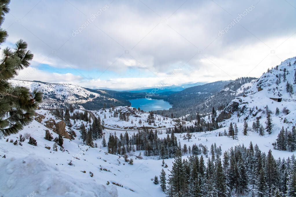 The Donner lake under the snow in winter, in California, panorama, with tunnels in the mountain for the train