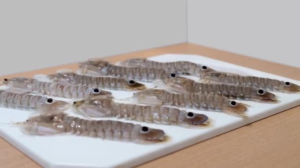 Сырые креветки-богомолы двигаются по кухонной доске — стоковое видео