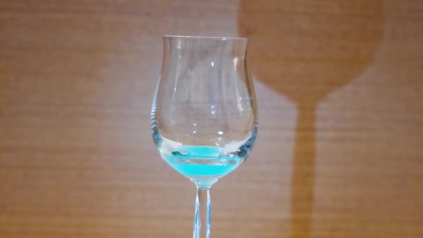 Azul alcohólico llena una copa de cristal elegante — Vídeo de stock