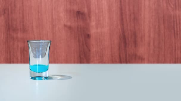 Schot glas is gevuld met blauwe vloeistof — Stockvideo