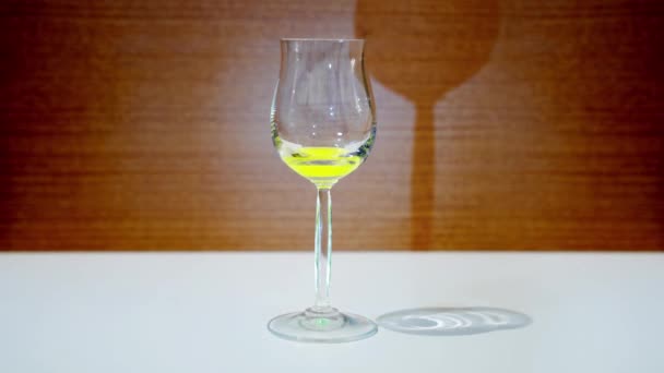 Gobelet de verre rempli de liquide jaune — Video