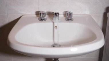 Banyo musluğu açılır ve su dışarı çıkar.