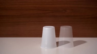 Plastik bardaklar, piramit şeklinde durgun bir hareketle ortaya çıkar.