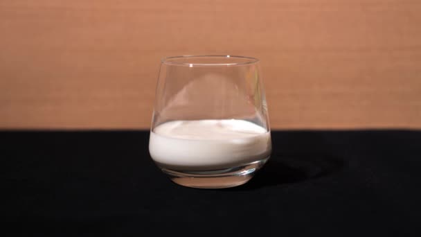 O leite é derramado no copo de vidro — Vídeo de Stock