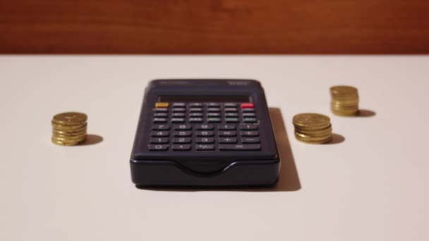 Monedas aparecen alrededor de una calculadora — Vídeos de Stock