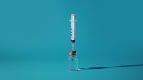 Spuit zuigt de vloeistof op uit een glazen injectieflacon — Stockvideo