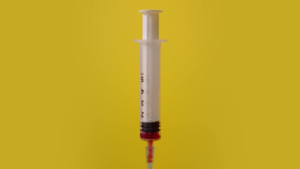 Injekční stříkačka čerpá červenou tekutinu na žlutém pozadí — Stock video