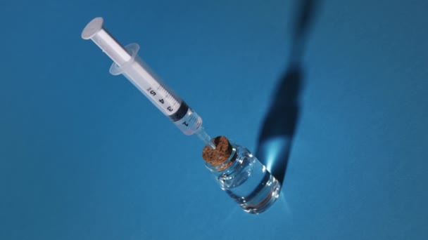 Spuit zuigt de vloeistof op uit een glazen injectieflacon — Stockvideo