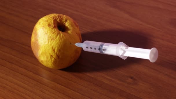 Syringe gives an injection into the rotten green apple — Stock Video