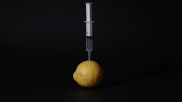 Syringe gives an injection into the lemon — Stock Video