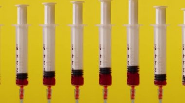 Many syringes fill with blood on a yellow background