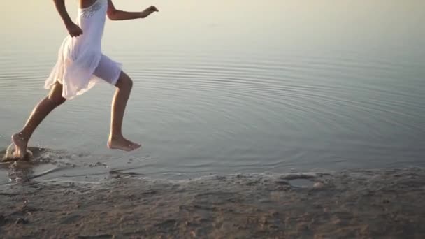 Девушка бежит по воде моря, а затем прыгает — стоковое видео