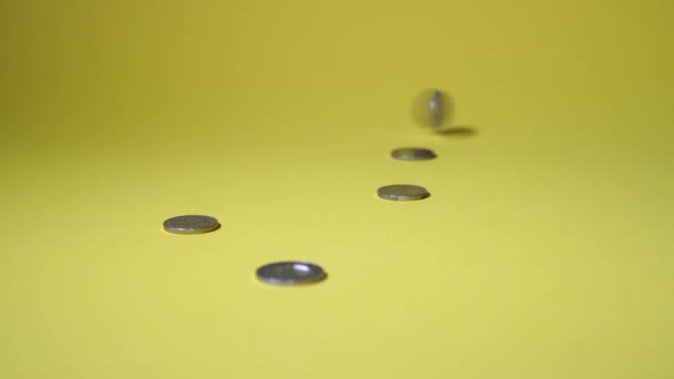 Coins appear on a yellow background turning — Stock Video