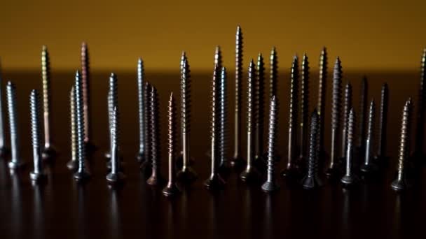 Steel screws on a dark background and lighting changes — Stock Video