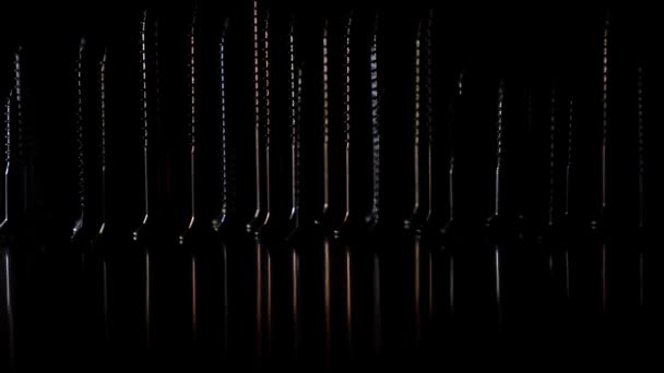 Tornillos de acero sobre fondo oscuro y cambios de iluminación — Vídeos de Stock