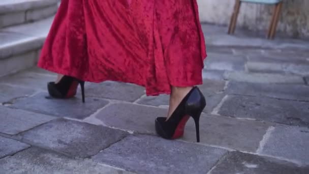 Piernas de niña en tacones con vestido rojo — Vídeo de stock