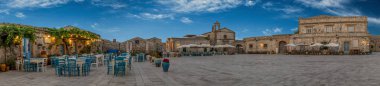 Panoramic view of the picturesque sicilian village Marzamemi, view of the traditional outdoor cafe and the church and the central square, province of Syracuse, Sicily, southern Italy clipart