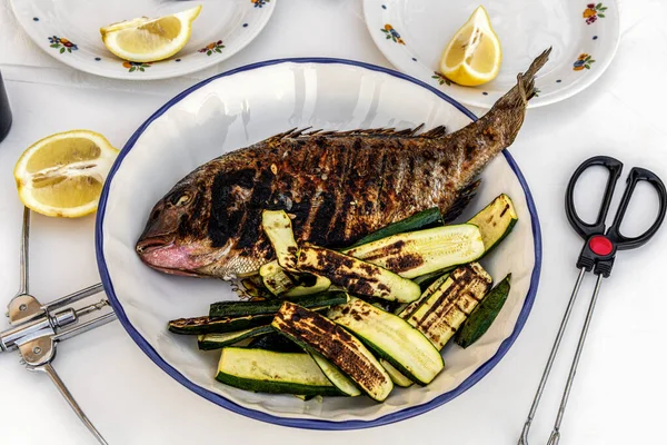 Kızarmış balık ve kabak, tabağında limon olan barbekü.