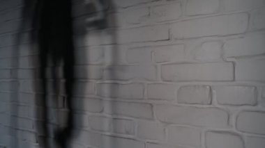 Duvarda hareket eden bir kızın gölgesi. Evde koşu bandında koşan bir kız. Çerçevede, evinde koşu bandında koşan bir kızın gölgesi var..