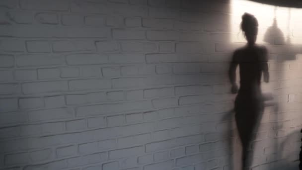 壁に少女の影が動いている ホームのトレッドミルを走る少女 フレームは自宅のトレッドミルを走る少女の影 — ストック動画