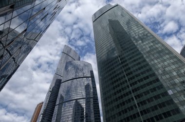 Aşağıdan gökdelenlerin manzarası. Gökdelenler mavi gökyüzüne karşı. Yüksek bina. Şehrin iş merkezi. Modern şehir mimarisi. Camdan ve betondan yapılmış evler.