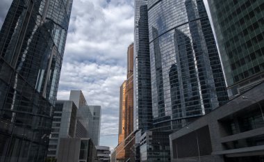 Aşağıdan gökdelenlerin manzarası. Gökdelenler mavi gökyüzüne karşı. Yüksek bina. Şehrin iş merkezi. Modern şehir mimarisi. Camdan ve betondan yapılmış evler.