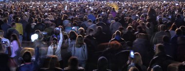 Parlak sahne ışıkları önünde bir konserdeki kalabalık..