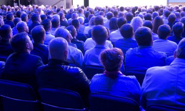 İnsanlar bir basın toplantısında koridorda oturuyorlar..