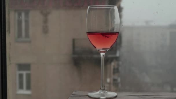 在雪缓缓落下的城市的背景下 一杯玫瑰酒 — 图库视频影像