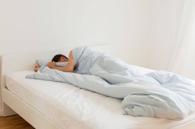 Beyaz bir yatakta uyuyan adam