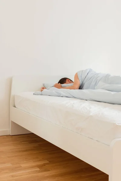 Mann schläft auf einem weißen Bett — Stockfoto