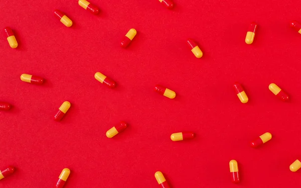 Czerwono-pomarańczowe tabletki w kapsułce na czerwonym tle — Zdjęcie stockowe