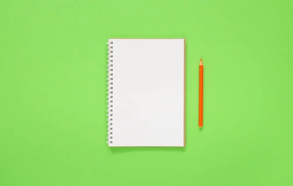 Yeşil arkaplanda spiral bir not defteri aç, defter ve kalem dokunun üzerine uzan, düz konsept