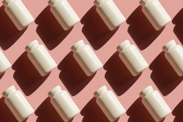 Powtarzające się białe puszki tabletek na różowym tle — Zdjęcie stockowe