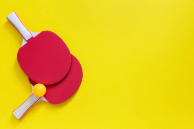 Kırmızı tenis pinpon raketleri ve turuncu top.