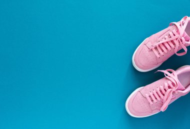 Turkuaz mavi arka planda izole edilmiş pembe spor ayakkabılar.