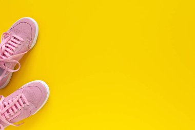 Sarı arka planda izole edilmiş pembe spor ayakkabılar.