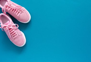 Turkuaz mavi arka planda izole edilmiş pembe spor ayakkabılar.
