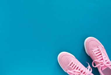 Turkuaz mavi arka planda izole edilmiş pembe spor ayakkabılar.