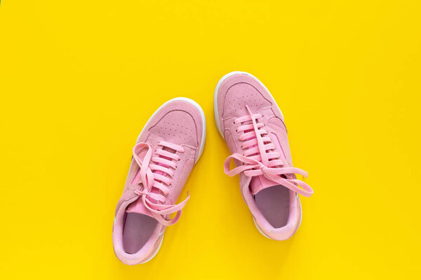 Pink sneakers isolated on a yellow background