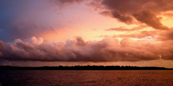 Bulut banka vurgulanan günbatımı deniz manzarası. 