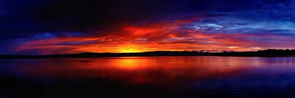 Драматический золотой и голубой облачный восход солнца над океанской водой . — стоковое фото