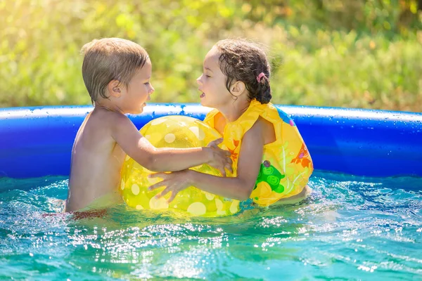 El niño pequeño está salpicando en la piscina inflable al aire libre — Foto de Stock